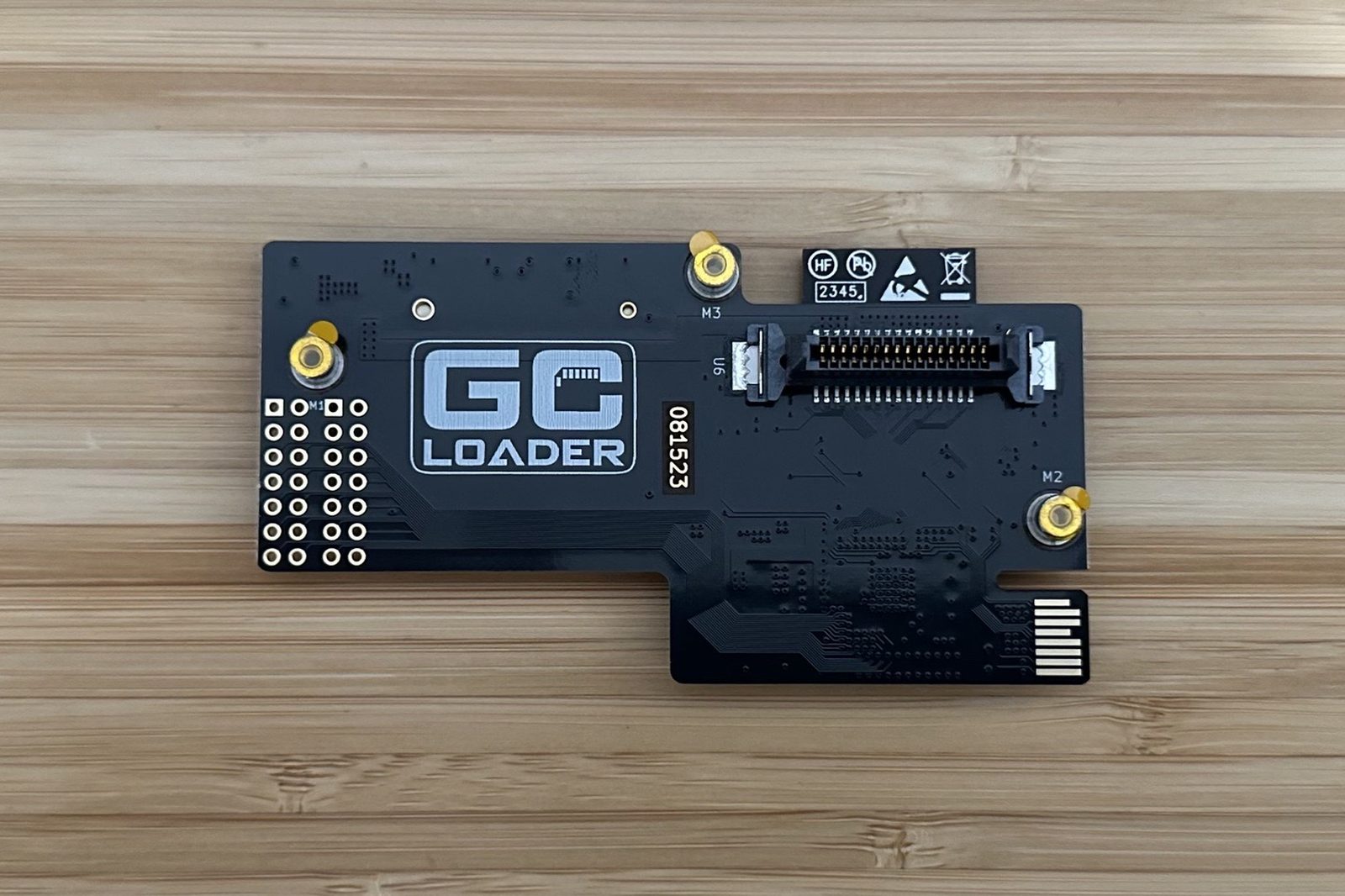 The GC Loader board, logo side up, showing its ribbon connector and mounting standoffs