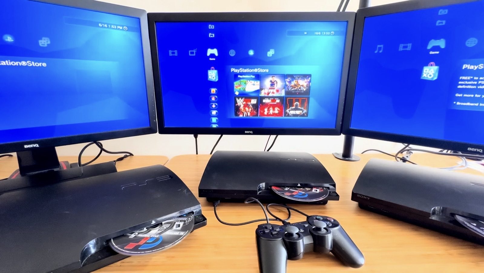 Three PlayStation 3 consoles wired up to three BenQ monitors, all booted to the PlayStation Store